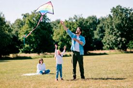 Семья запускает радужного воздушного змея в парке
